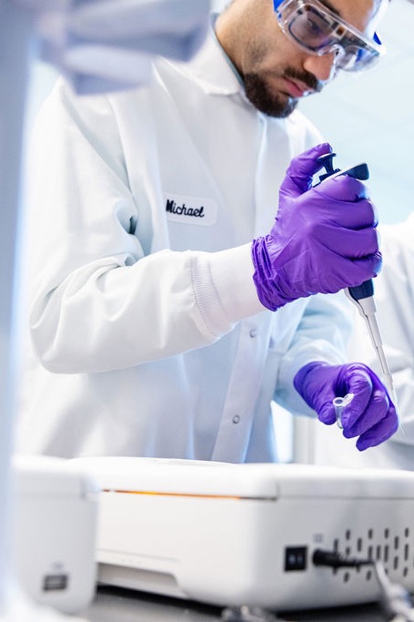 BiomEdit scientist in a lab coat and safety glasses using a pipette