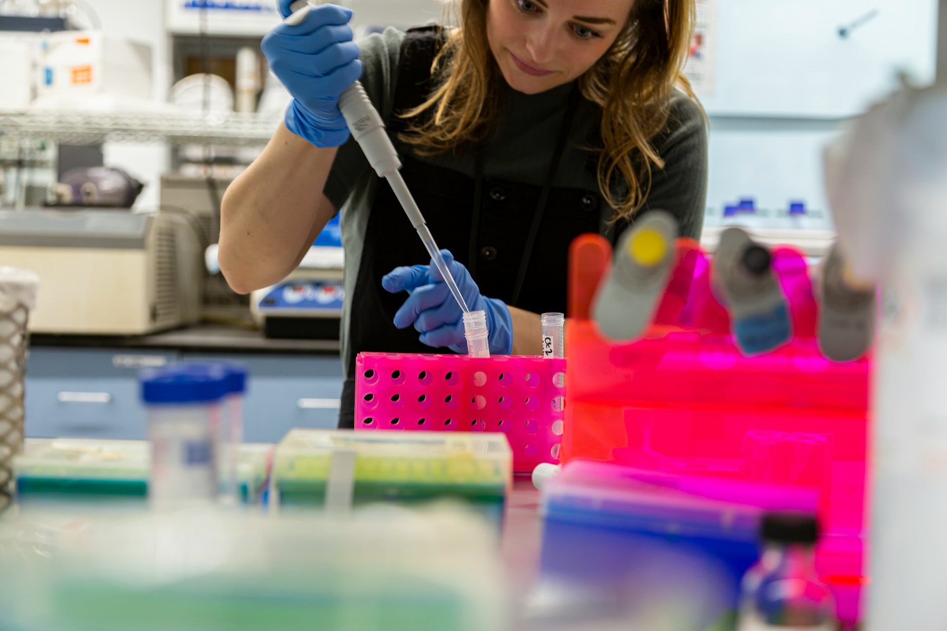 Scientist pipetting samples into a test tube rack in a laboratory